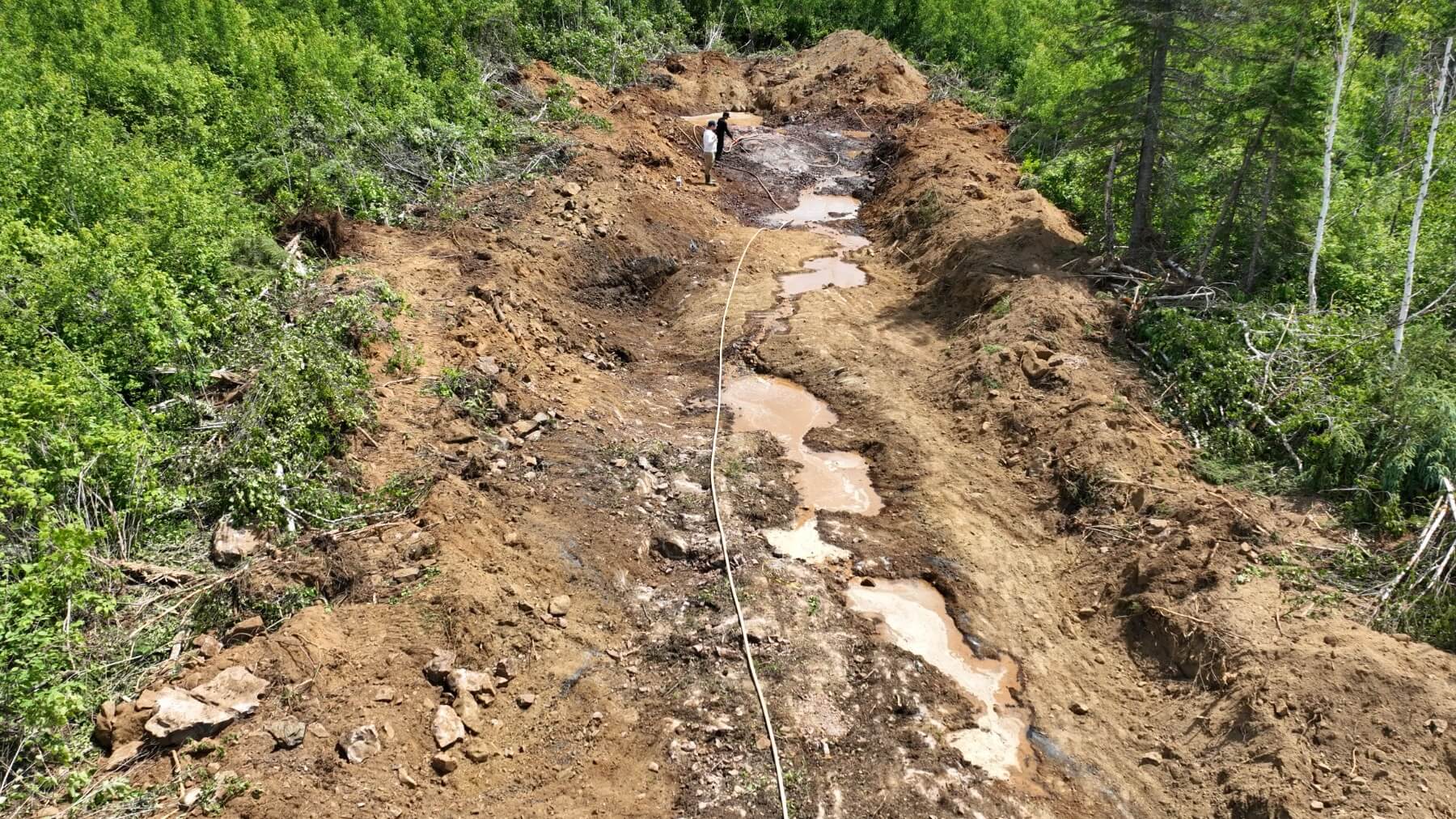 Photo 1. Exploration team washing a newly exposed felsic dike during trenching approximately 100 metres south of the I-Zone to prepare the outcrop for geological mapping and channel sampling.